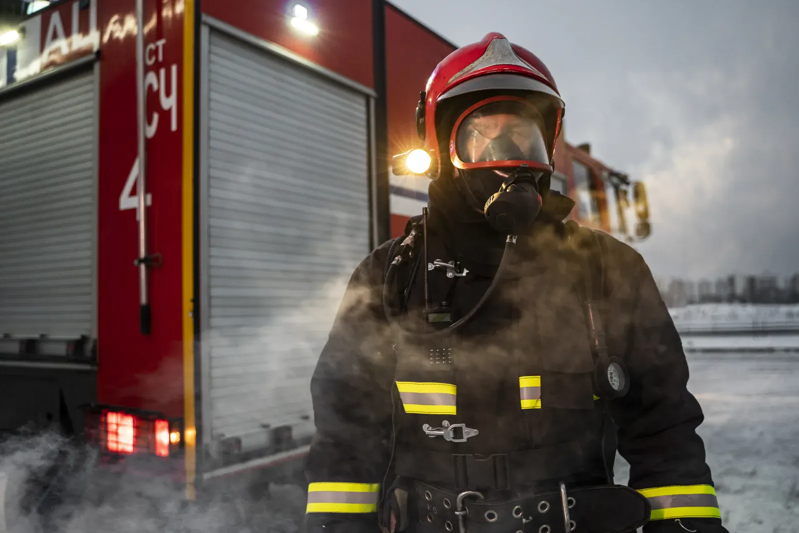 Firefighter in protective equipment beside an emergency response vehicle