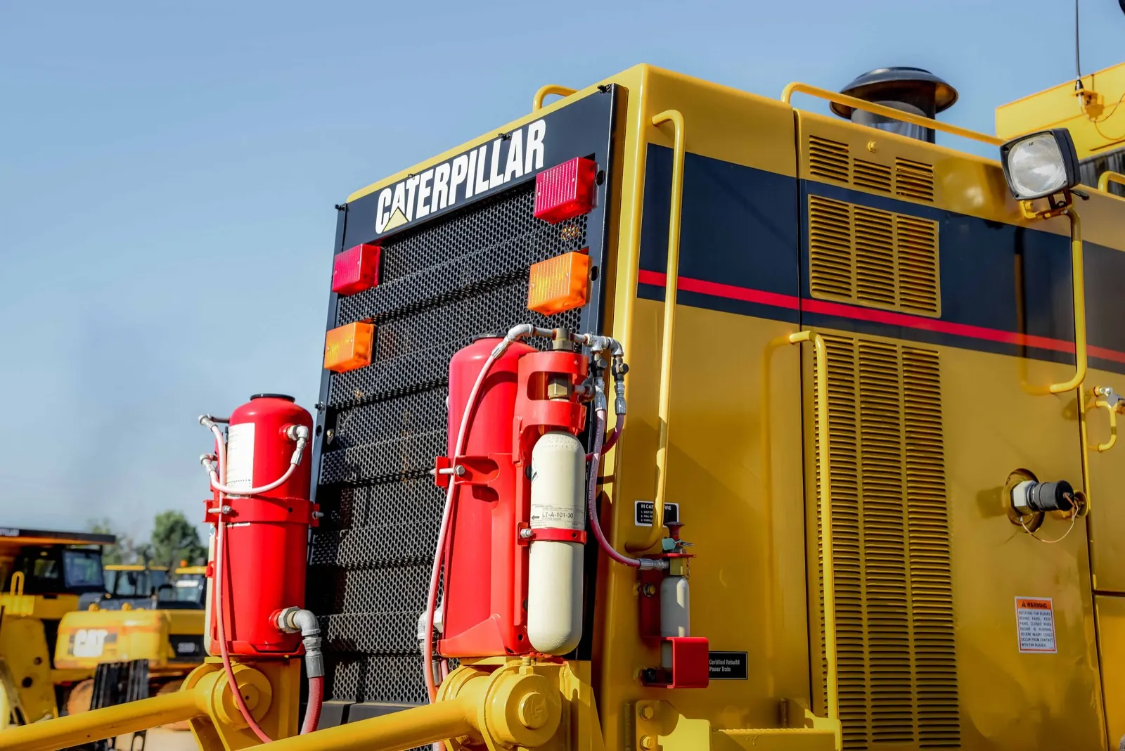 Close-up of red fire suppression tanks and hoses mounted on Caterpillar heavy equipment